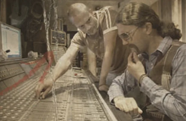 Kef and Charlie Bunkum leaning over a large mixing console